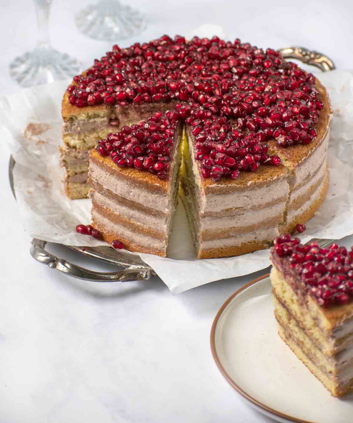 whole pomegranate mousse cake sliced with slice out on a plate in the foreground