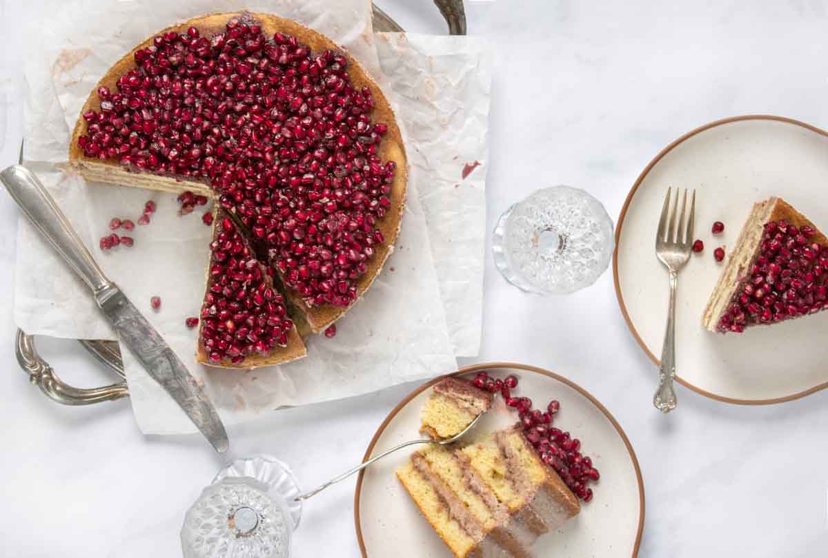 overhead view of whole pomegranate cake with slices on two plates 