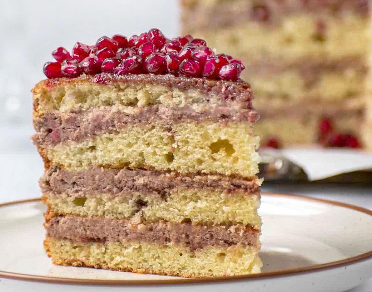 slice of pomegranate mousse cake with whole cake in the background