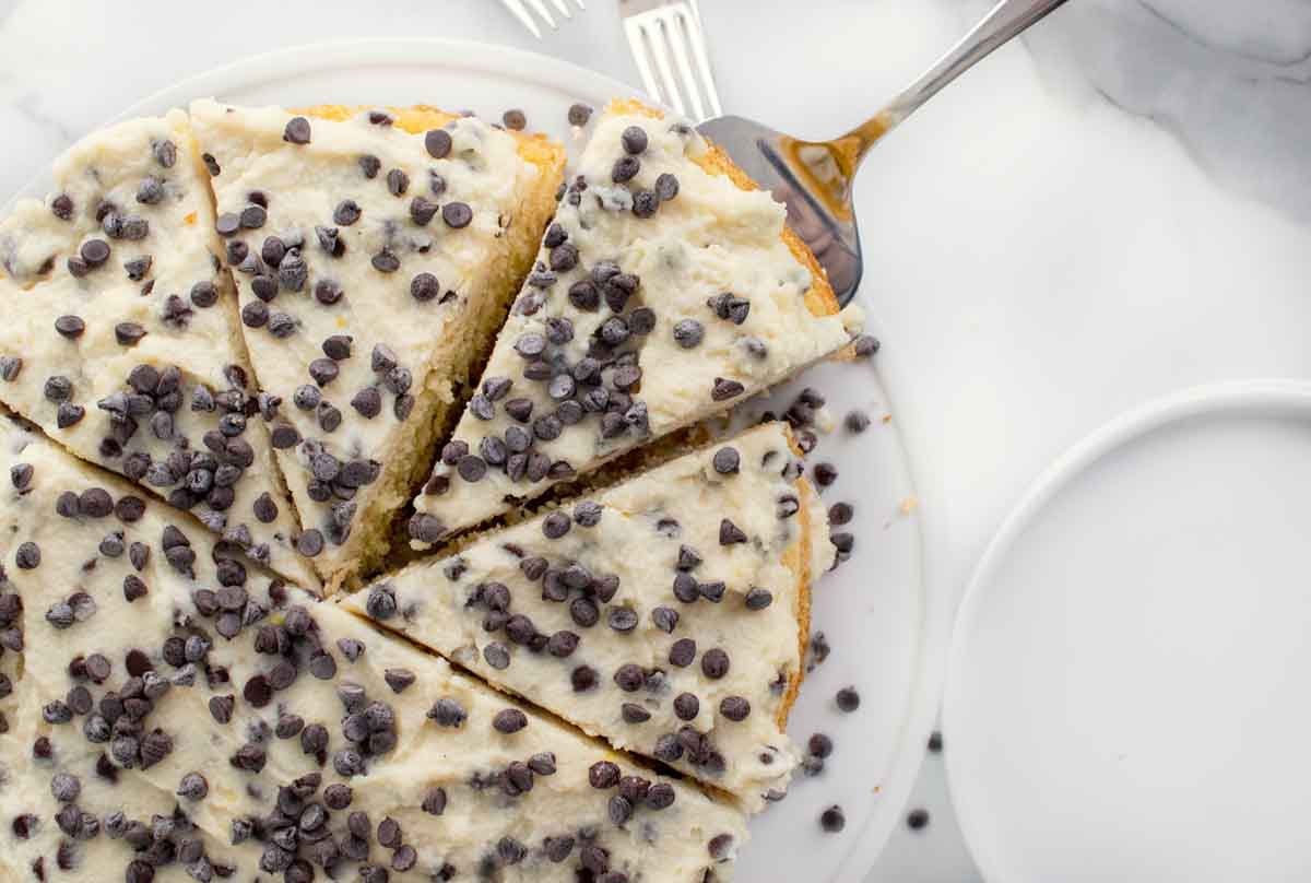 overhead view of whole cheesecake sliced with a slice on a cake spatula