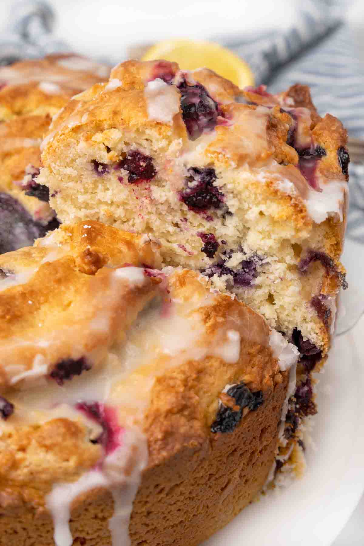 Slice of lemon blueberry pound cake being taken out of whole cake.