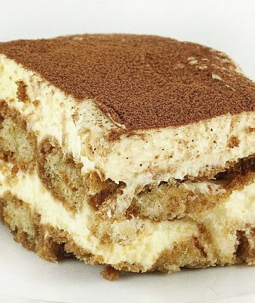 slice of tiramisu with a dusting of cocoa sitting on a white plate