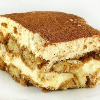 slice of tiramisu with a dusting of cocoa sitting on a white plate