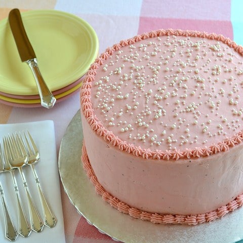 whole decorated strawberry kiss cake on a white cake stand