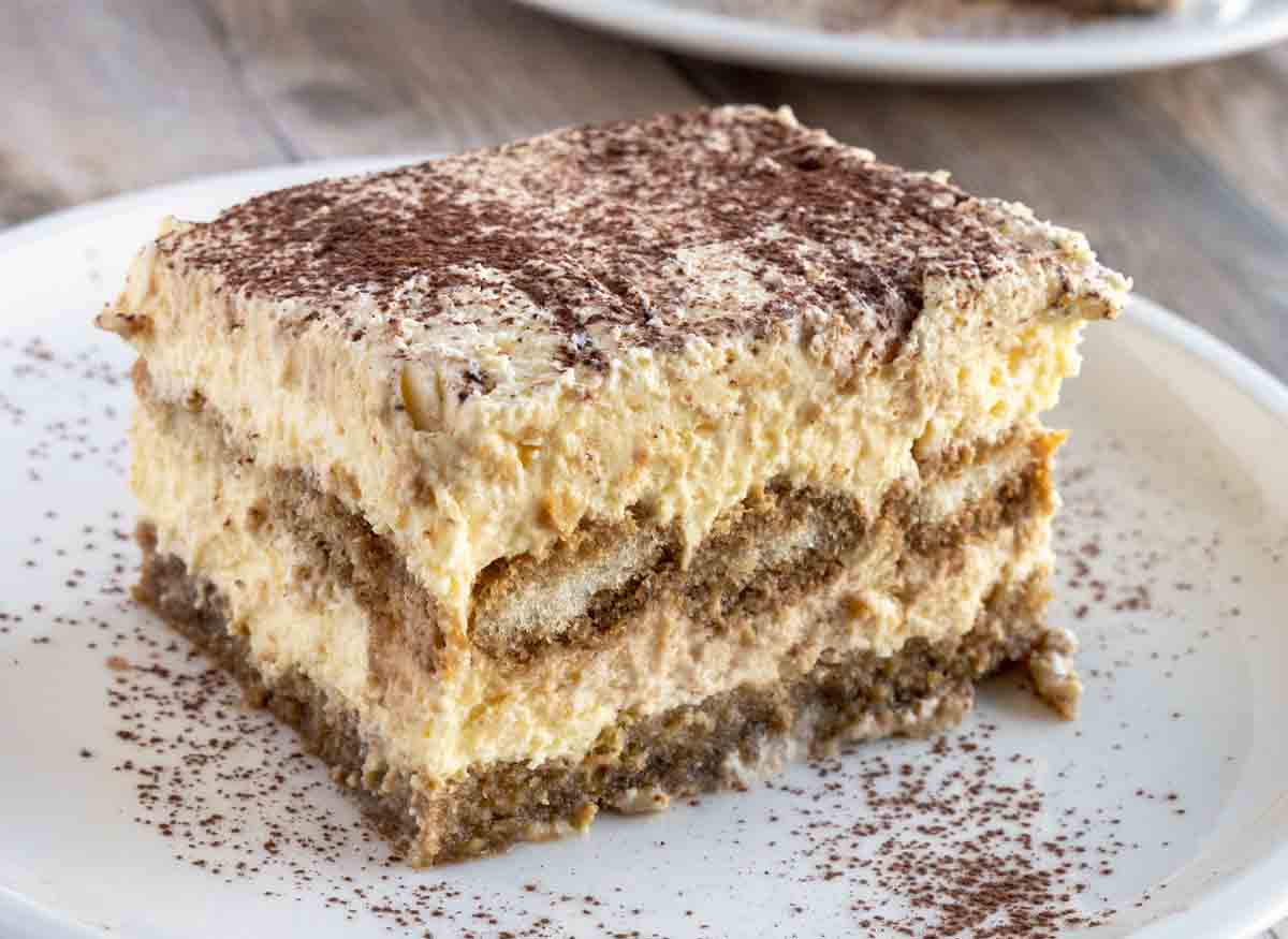 slice of tiramisu sprinkled with cocoa powder on a white plate.