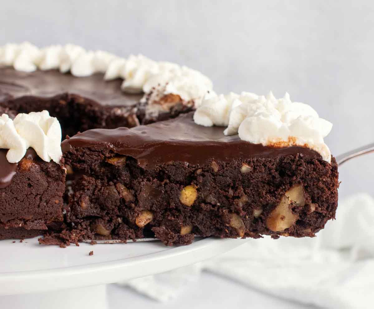 slice of chocolate torte on a spatula being taken out of the whole cake