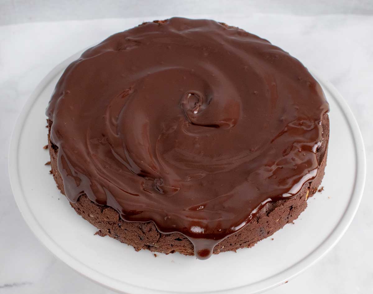 whole chocolate torte with chocolate topping on a white platter