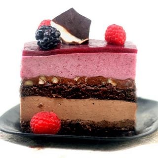 slice of entremet topped with berries on a black plate