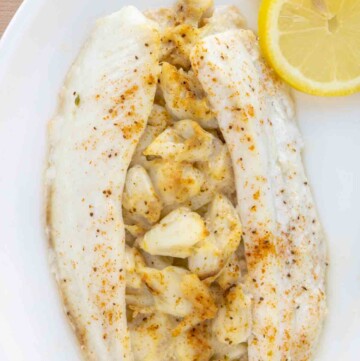 overhead view of stuffed flounder on a white plate with lemon circles