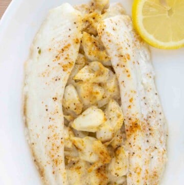 overhead view of stuffed flounder on a white plate with lemon circles