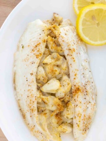 overhead view of stuffed flounder on a white plate with lemon circles