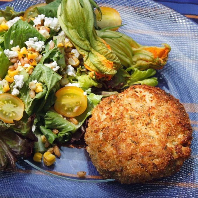 Famous Lump Crab cake on a glass plate with a salad on the side