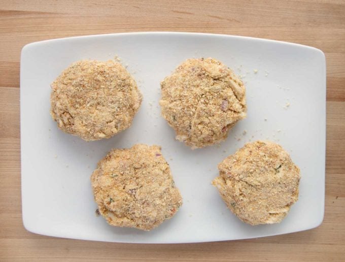 overhead view of 4 breaded crab cakes on a white platter