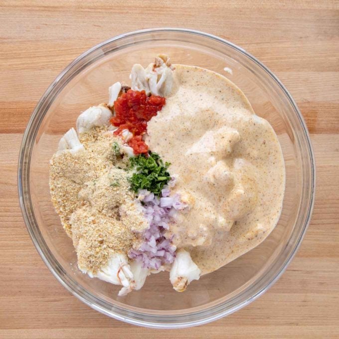 bowl with all the ingredients to make crabcakes on a wooden cutting board