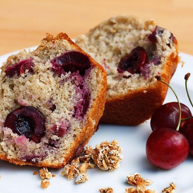 cherry vanilla muffin split sitting a white plate with whole cherries