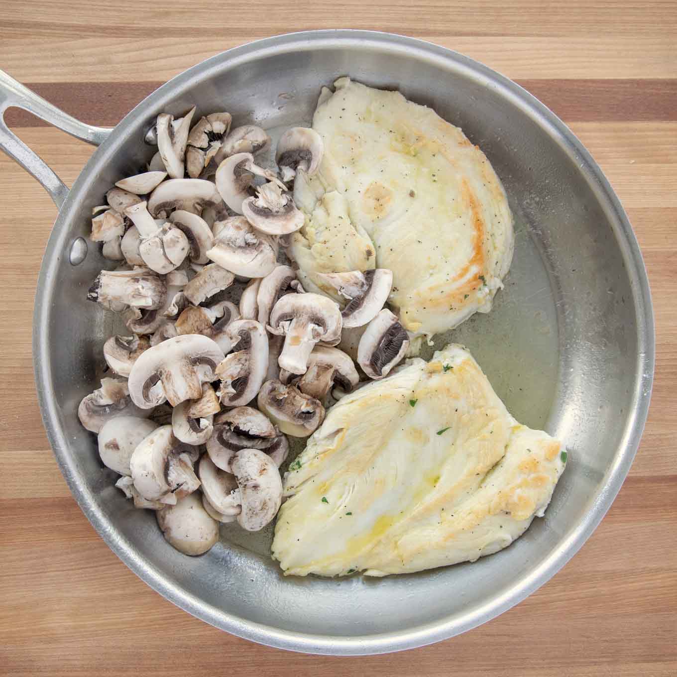 2 chicken breasts and mushrooms in a saute pan