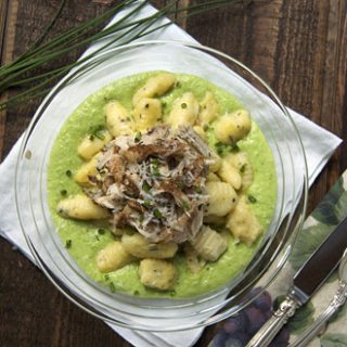 overhead view of potato gnocchi over pureed peas on a clear plate