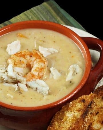 brown crock of shrimp and crab chowder with toasts on a white plate