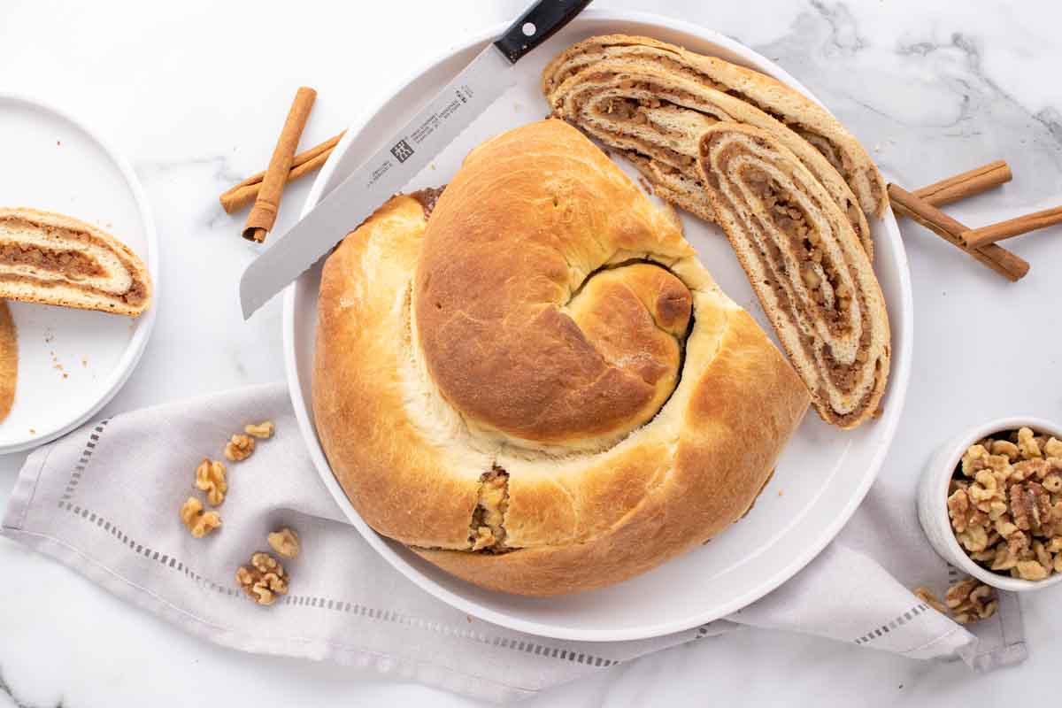 overhead view of sliced potica with loaf on a white plate