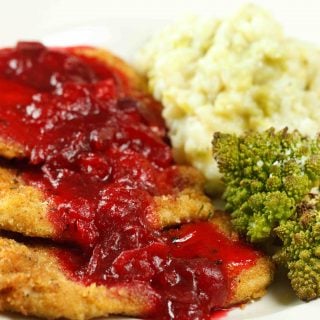 close up of turkey Milanese with a cranberry sauce next to romanesco and mashed potatoes