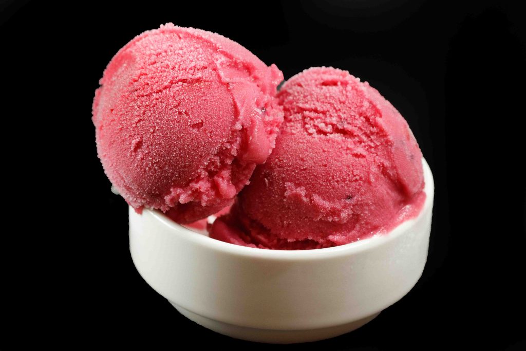 small white bowl of cranberry gelato on a black background