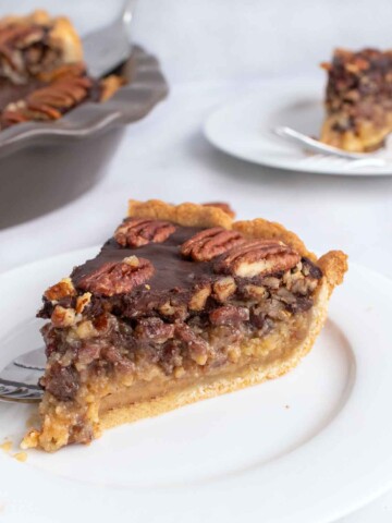 slice of pecan pie on a white plate with more in the background