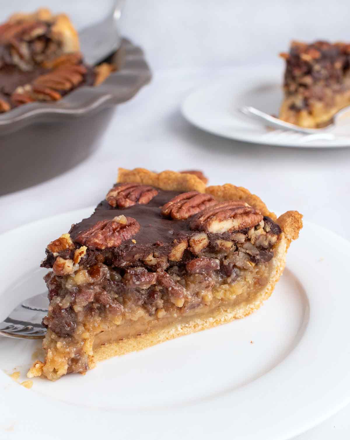 slice of pecan pie on a white plate with more in the background