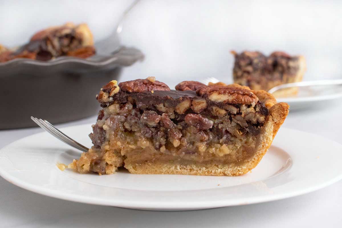 side view of a slice of pecan pie on a white plate