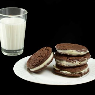 stack of triple chocolate cookies on a white plate next to a glass of milk