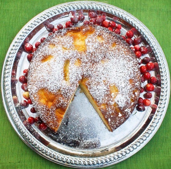 overhead view of torta di mele on a silver platter with a slice cut out