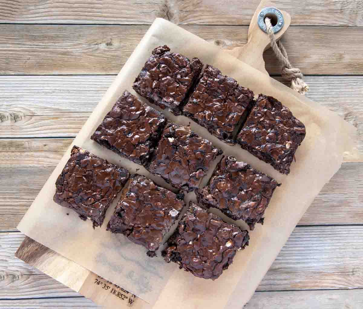 brownies cut and placed on parchment on a wooden cutting board