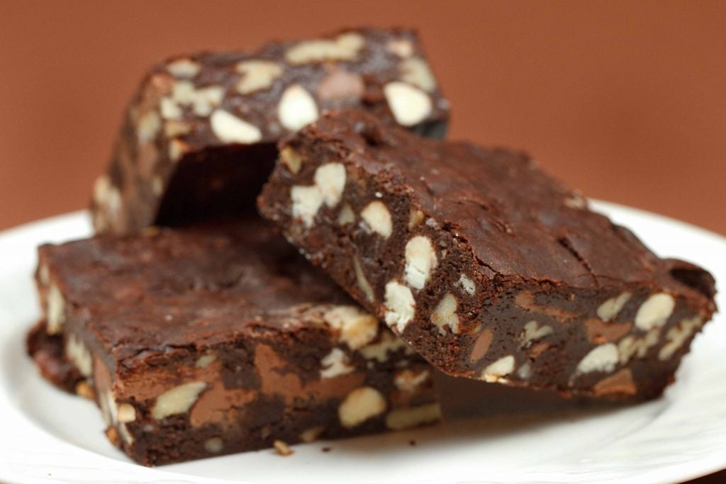 stack of Triple Chocolate Pecan Brownies on parchment paper