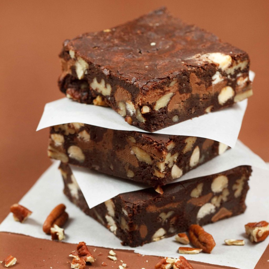 stack of three Triple Chocolate Pecan Brownies separated with white parchment paper