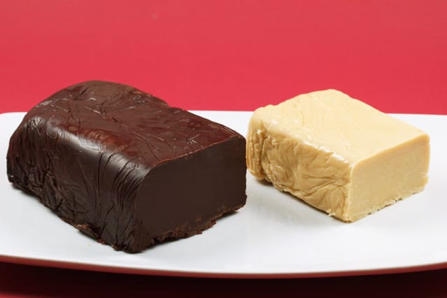 loaf of dark chocolate pate and loaf of white chocolate pate on a white plate on a red backgrounc