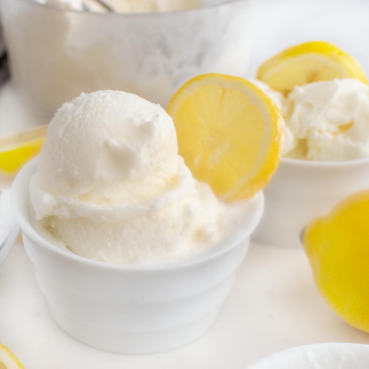 scoops of lemon gelato in a bowl with a lemon slice