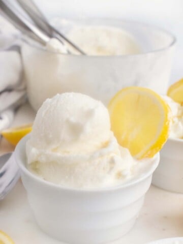 lemon gelato in a bowl with a wedge of lemon