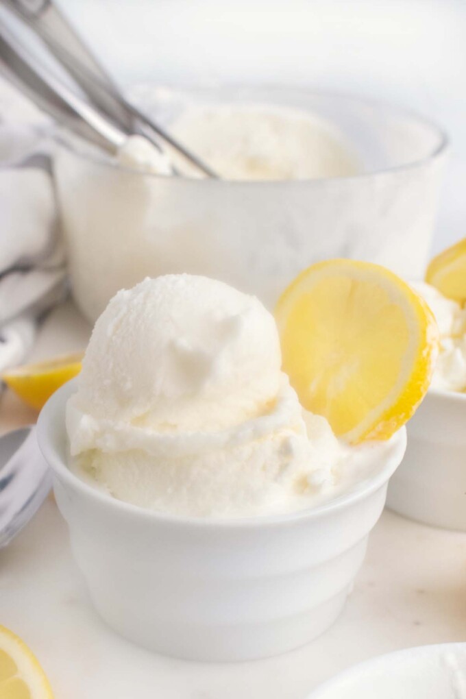 lemon gelato in a bowl with a wedge of lemon