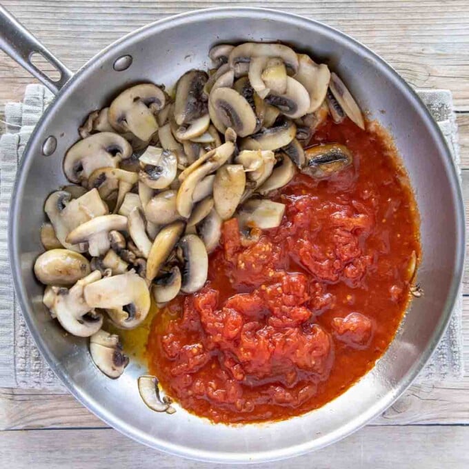 sauteed mushrooms in saute pan with added crushed tomatoes