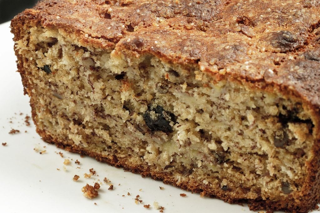 Blueberry oat Banana bread with Pecans missing the front slice on a white plate 