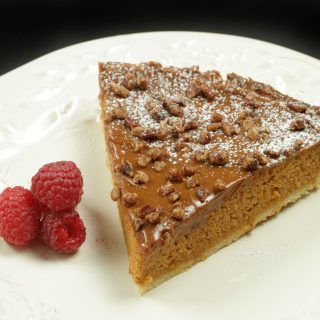 slice of butternut squash caramel torte on a white plate with raspberries