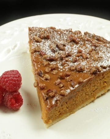 slice of butternut squash caramel torte on a white plate with raspberries
