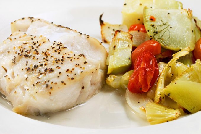 roasted seasoned golden tilefish with vegetables on a white plate