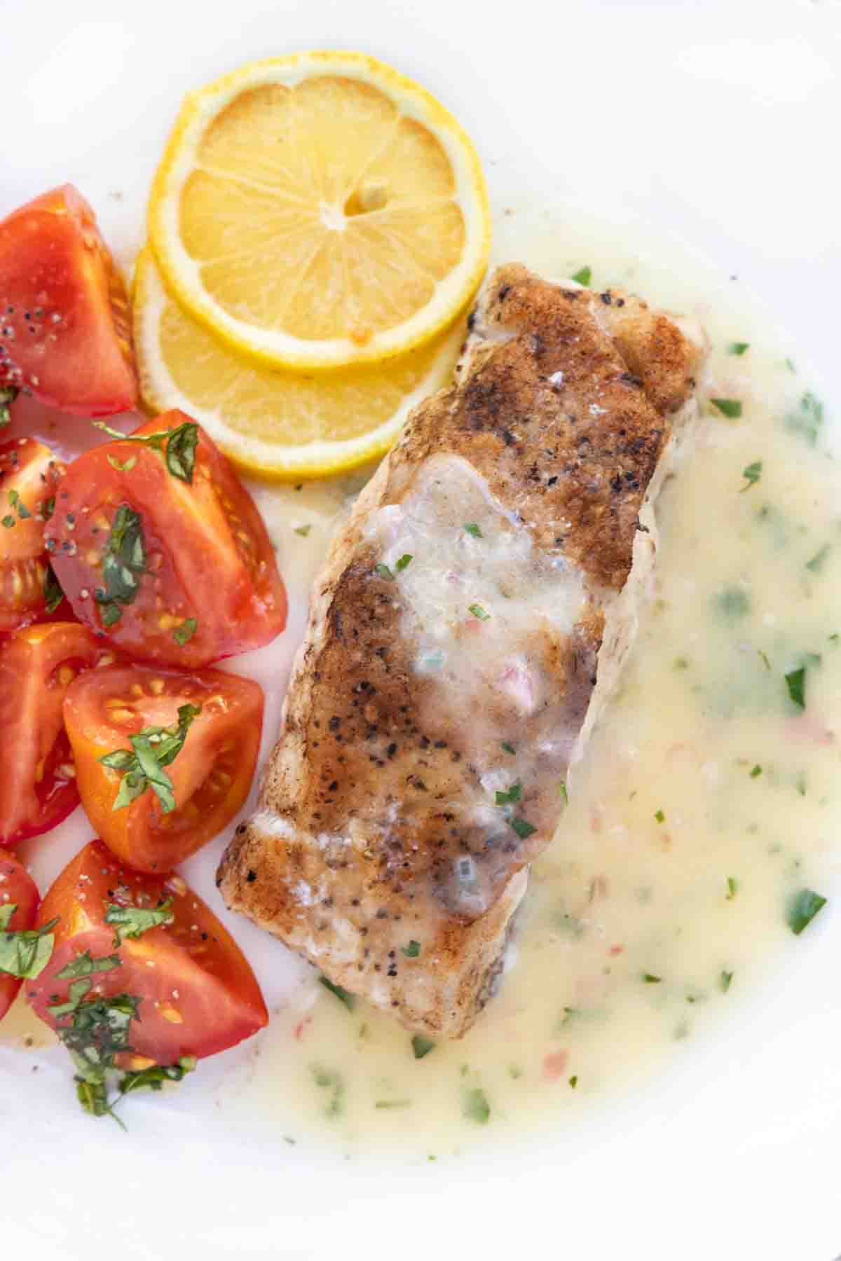 Pan seared tilefish with lemon butter sauce on white plate.