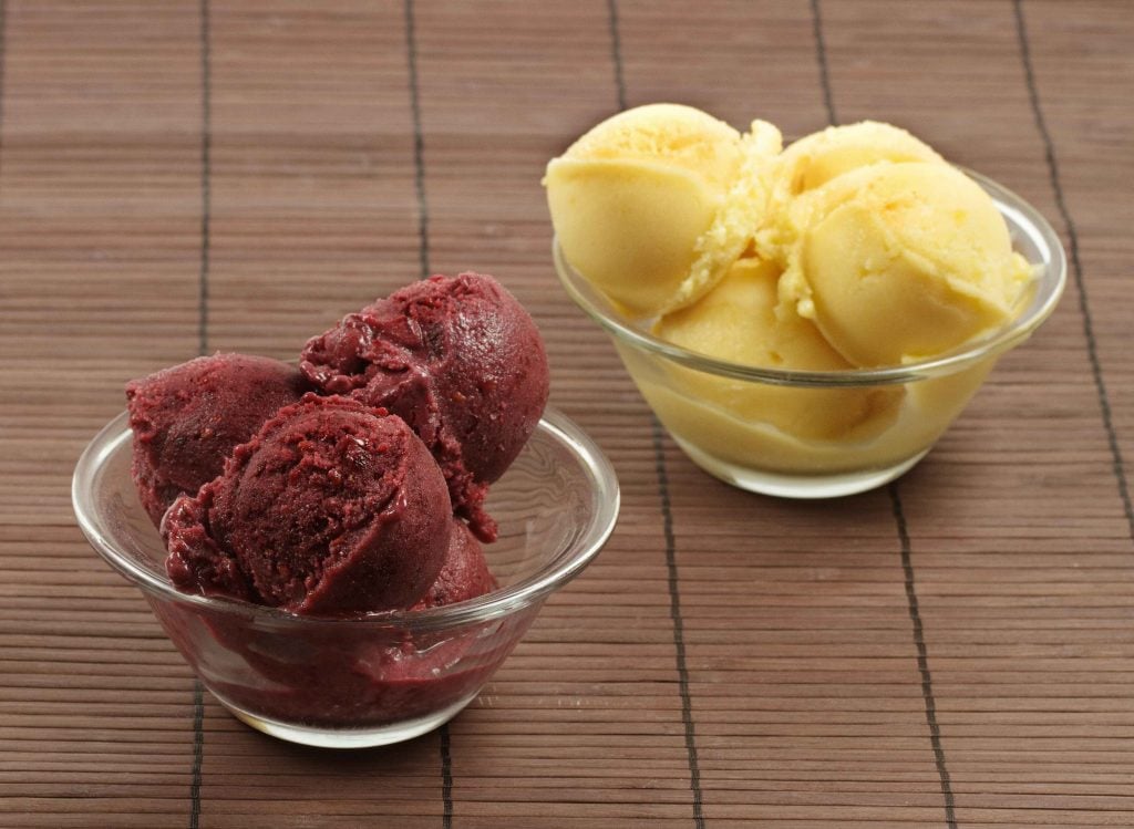 bowls of blackberry gelato and mango gelato on a wicker mat