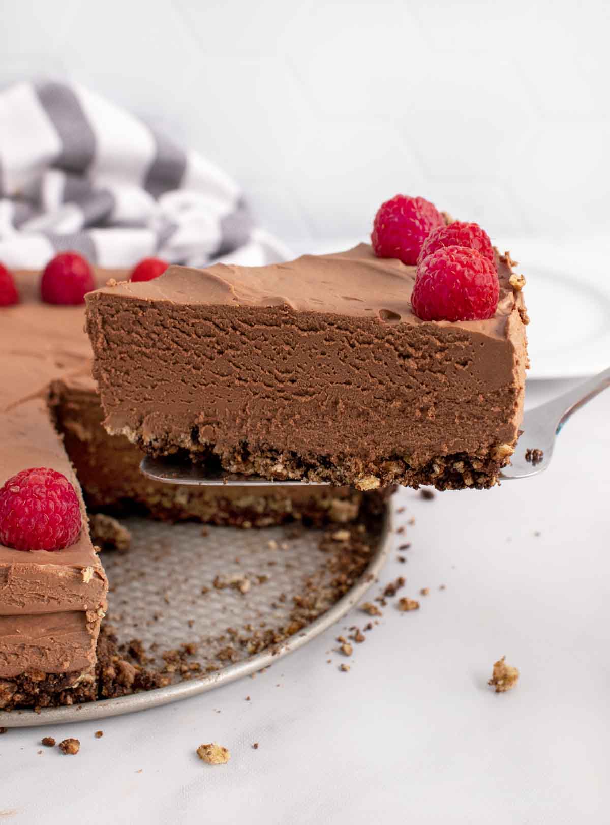 slice of no bake chocolate cheesecake on a spatula being taken out of the whole cake