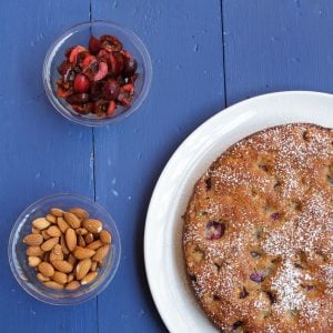 overhead partial view of cherry almond cake with bowls of cherries and almonds