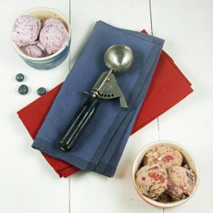 overhead view of two bowls of gelato and two napkins with an ice cream scoop on top