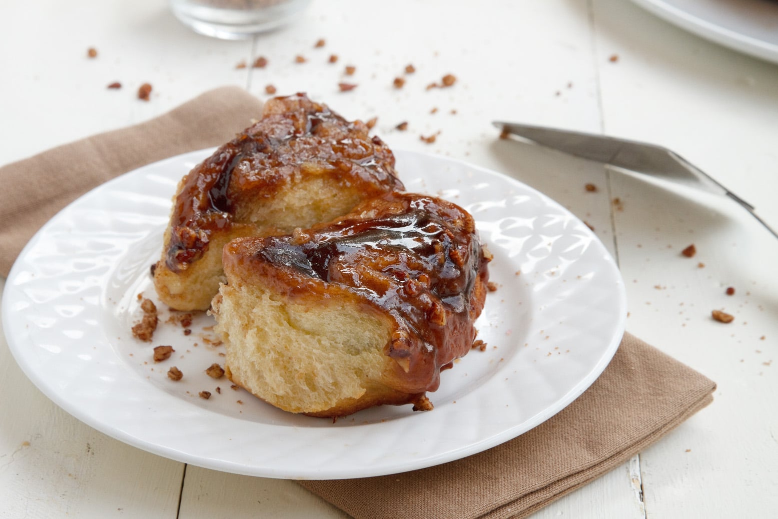 sticky buns on a white plate on top of a light brown napkin sitting on a white table