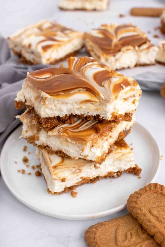 3 Biscoff swirl cheesecake bars stacked on a white plate