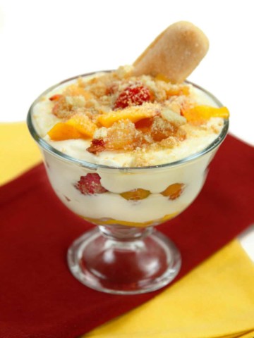 glass dish of peach tiramisu with a lady finger sticking out